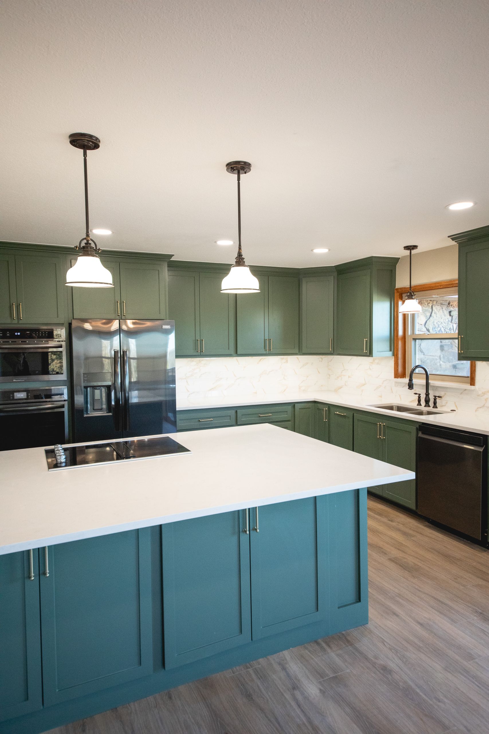 Kitchen island with pendant lighting, green cabinetry, and wood-look flooring.