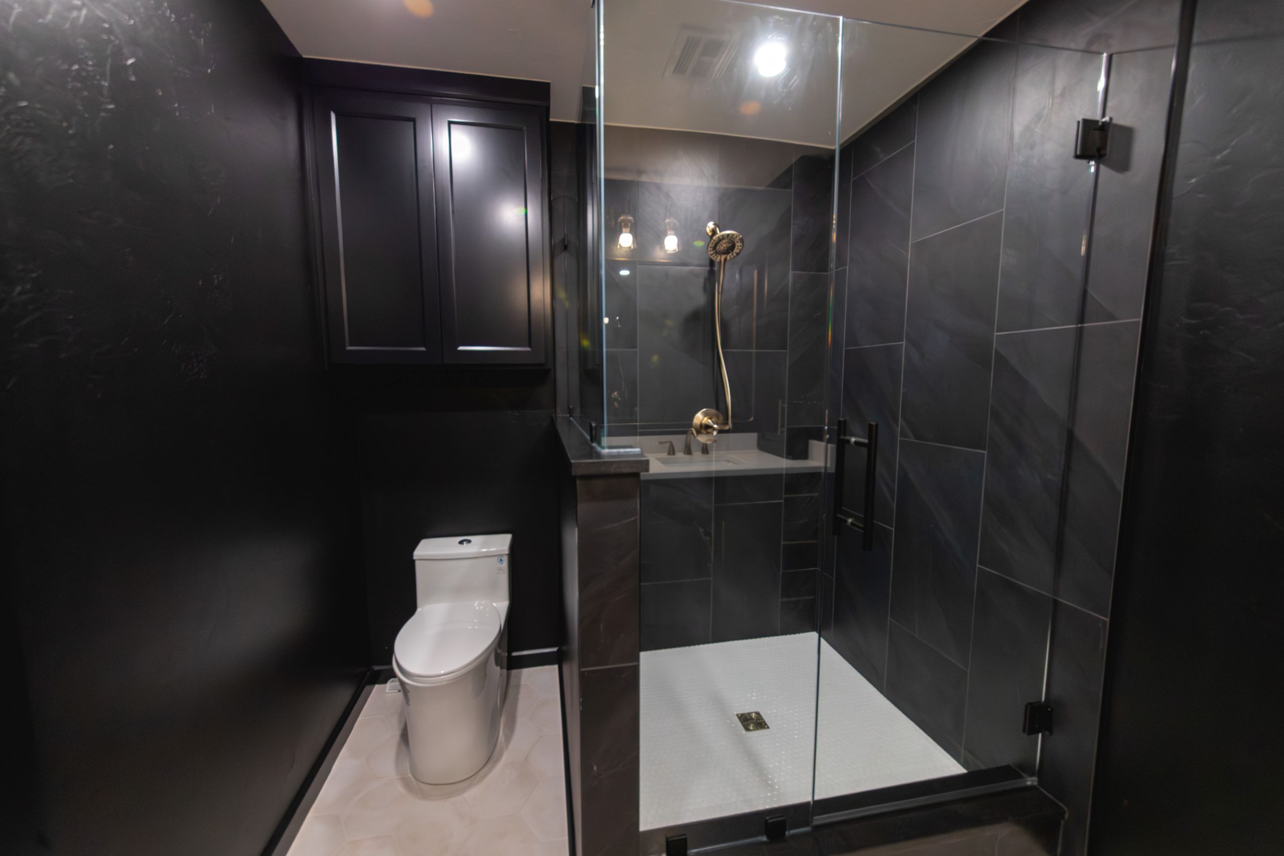 Toilet next to glass shower enclosure in a black-accented bathroom.