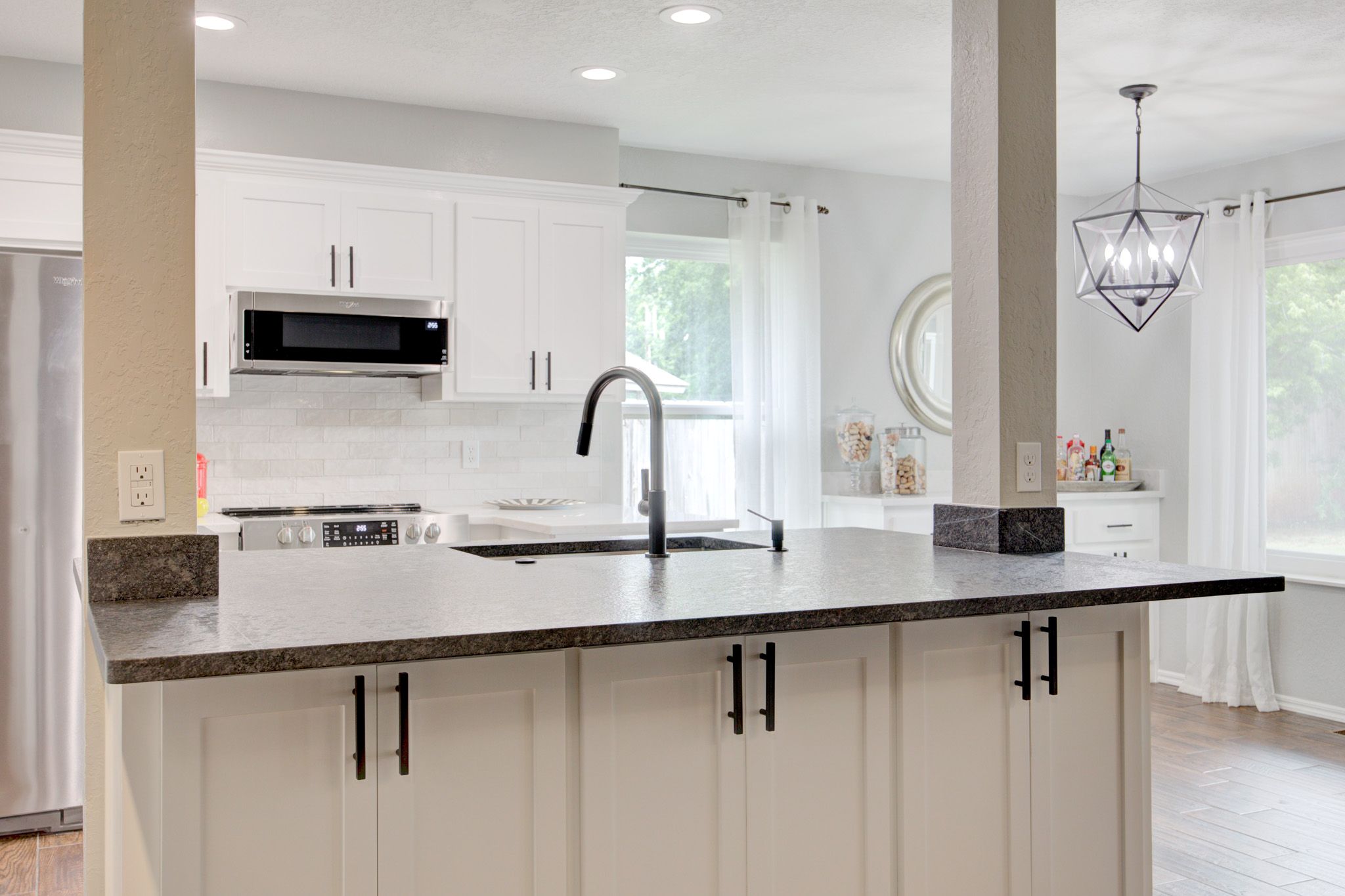 Modern kitchen with white cabinetry, dark countertops, and a central island with a black faucet.