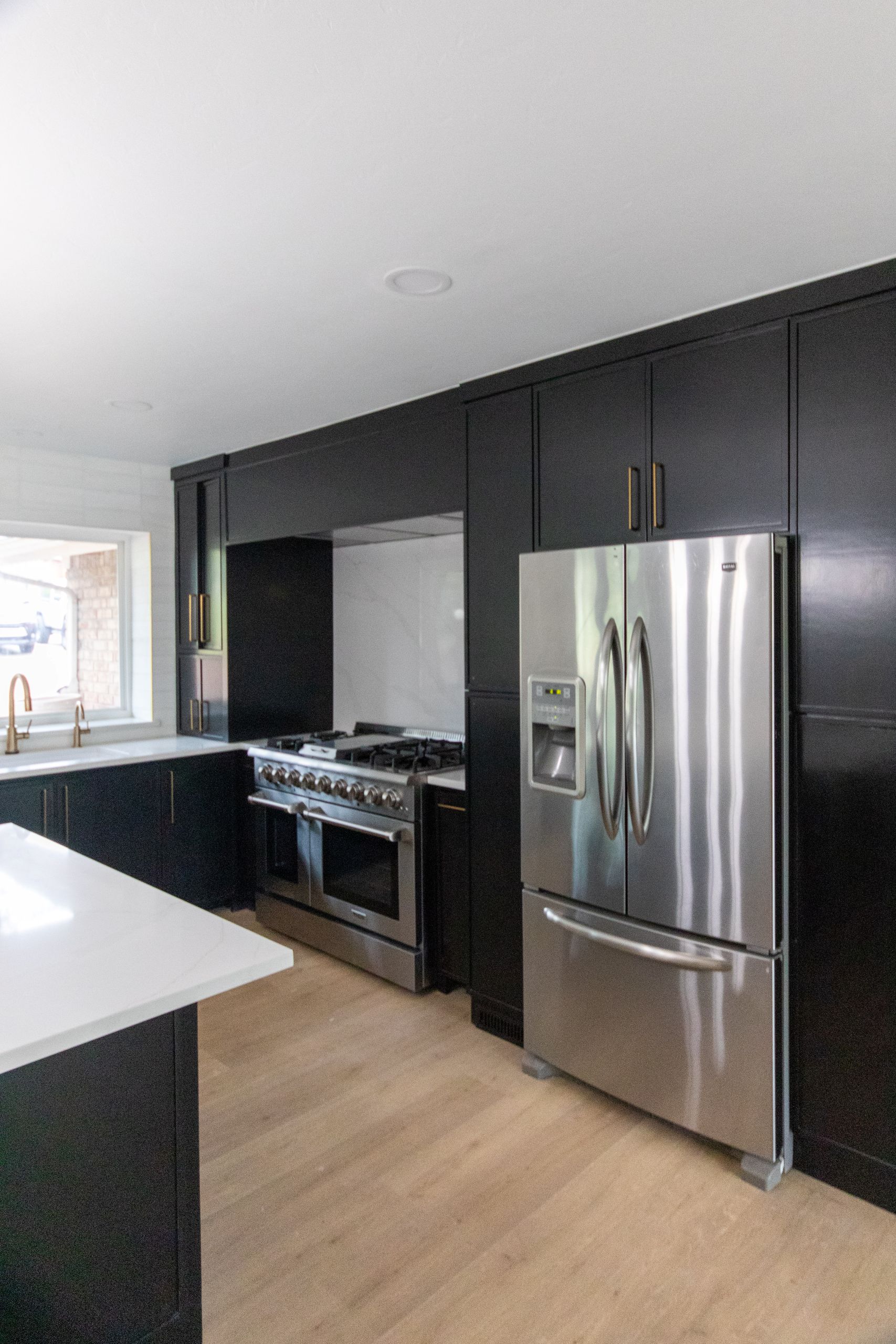 Contemporary kitchen with black cabinets, stainless steel refrigerator, and gas range