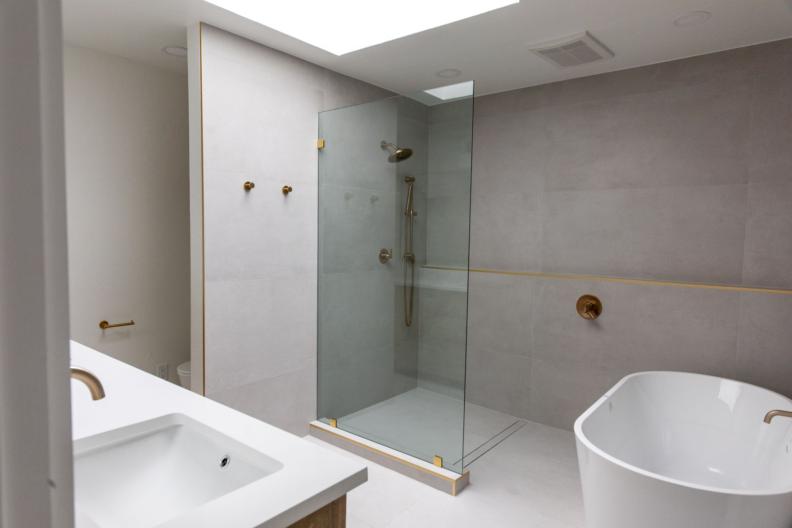 Modern walk-in shower with matte tile walls and brass rain shower fixture