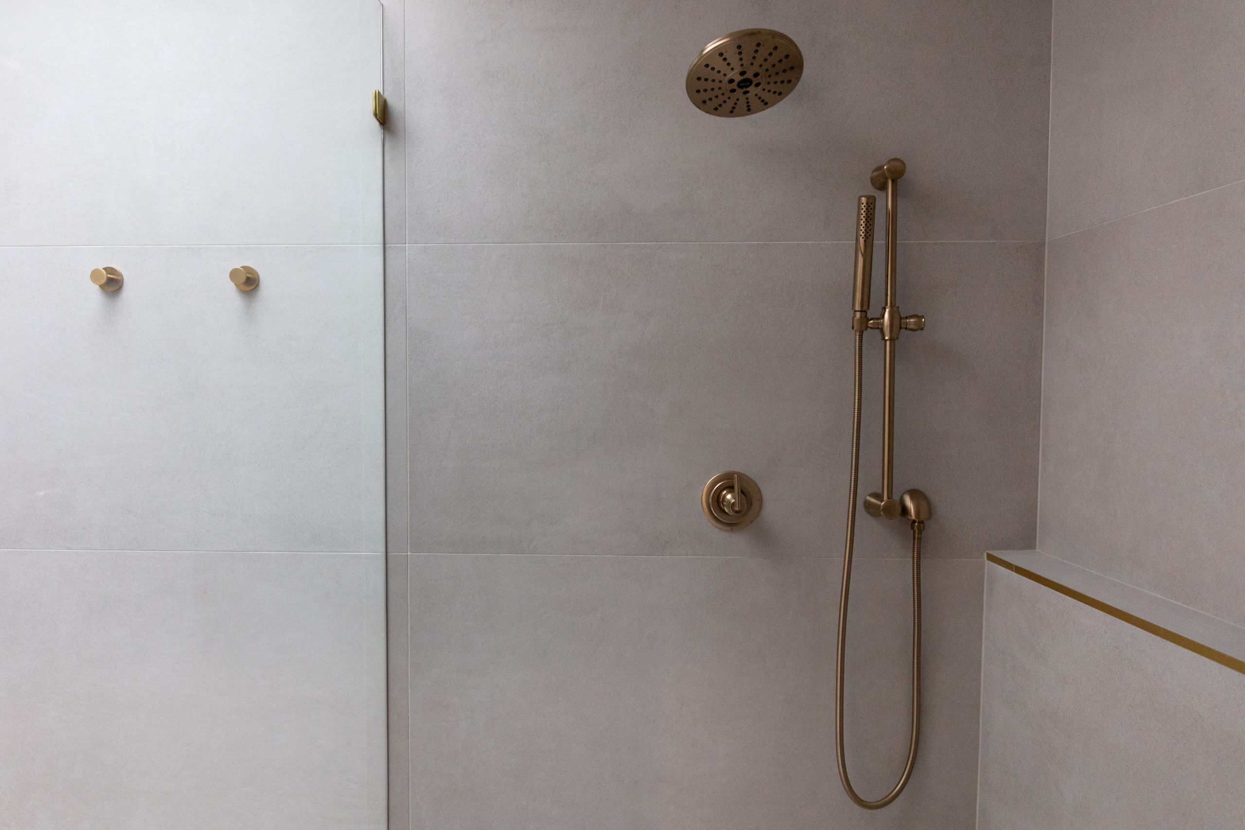 Modern walk-in shower with matte tile walls and brass rain shower fixture