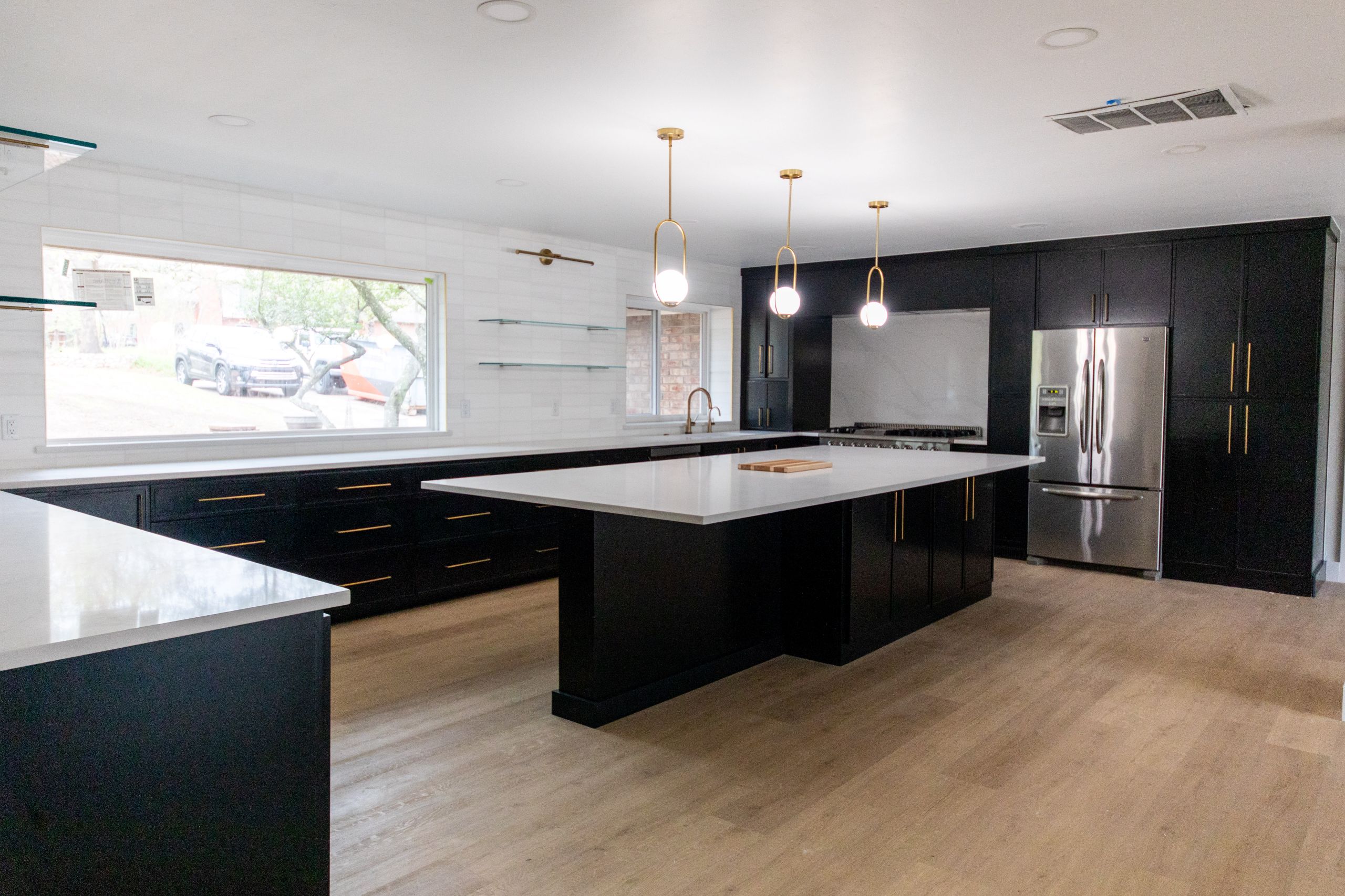 Modern kitchen with large island, black cabinetry, and gold pendant lighting