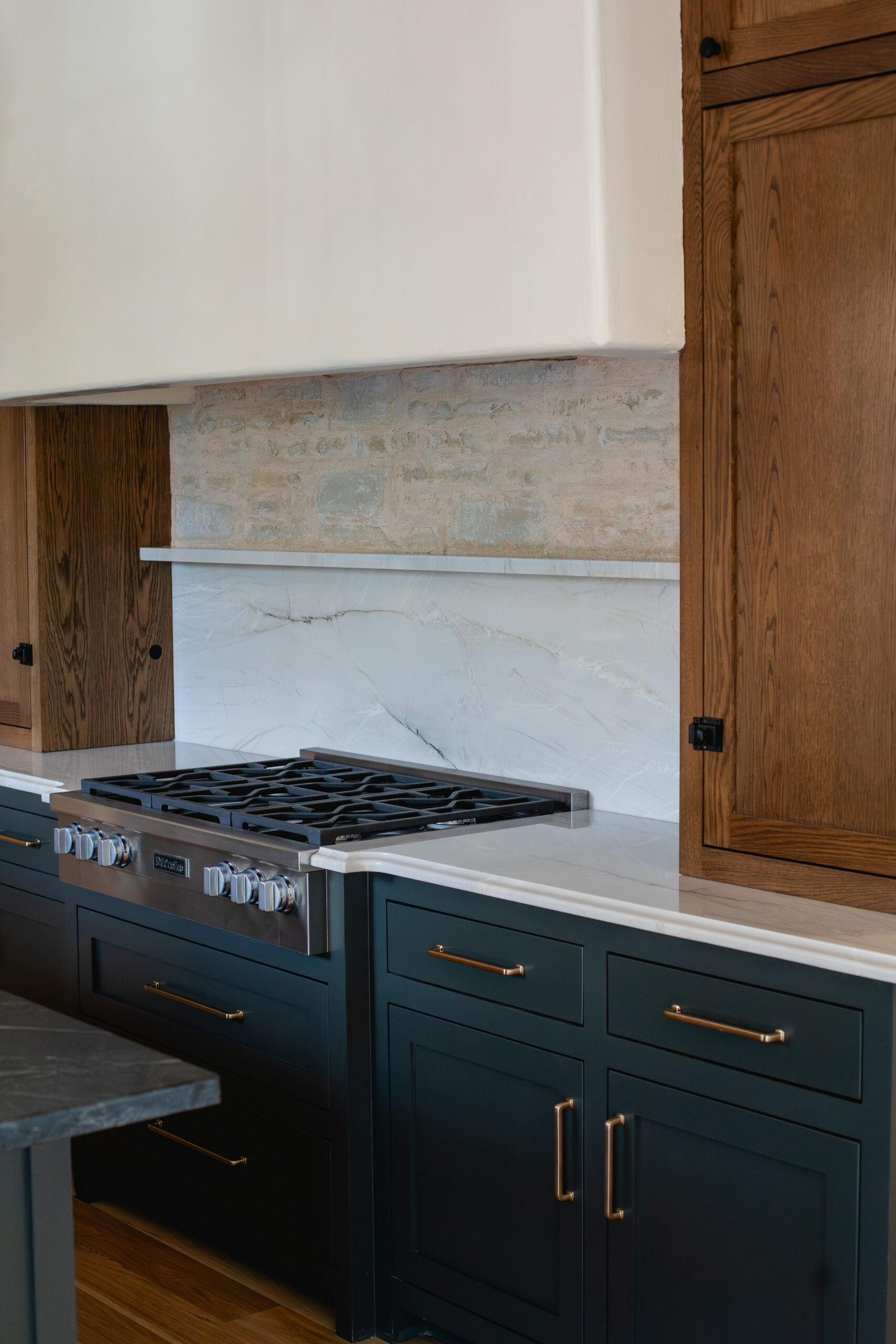 Modern kitchen with dark cabinetry, stone backsplash and stainless gas range.